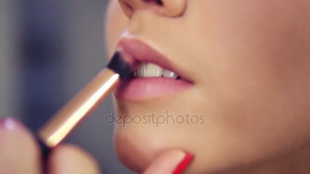 Artista de maquillaje profesional aplicando cartilla de lápiz labial en los labios del modelo que trabaja en la industria de la moda de belleza. Vista de primer plano de una mano de artistas usando un pincel especial — Vídeo de stock