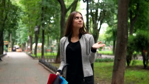 市内の公園に雨が降っているかどうか確認彼女の手で彼女のカラフルな傘を持つ若い魅力的なブルネットの女性の肖像画。その後、彼女は彼女の傘を開いています。スローモーション撮影 — ストック動画