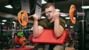 Genç yetişkin vücut geliştirmeci halter salonunda onun pazı eğitim yapıyor. Olanakları eşiğinde. 4 k'dan fazla vurdu