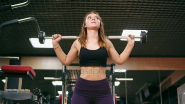 Önden Görünüm kısa top genç bir kadın ve tozluk salonunda bir halter, kalça ve bacak kaslarının iyileştirilmesi ile ağız kavgası yapıyor. 4 k'dan fazla vurdu