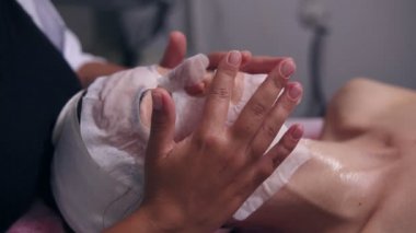 Apllying özel maske kadın istemcileri yüz ve boyun üzerinde ise kadının yüzünde ellerini tutarak profesyonel güzellik uzmanı. Spa salonda genç kadın için profesyonel Karboksiterapi
