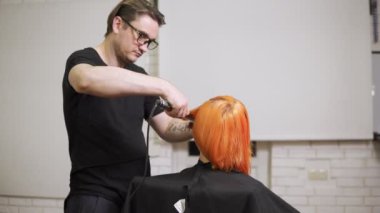 Yakın çekim shot saçlarını Kuaför Salonu içinde bir erkek profesyonel saç stilist tarafından doğruldu sahip bir kadın. 4 k'dan fazla vurdu