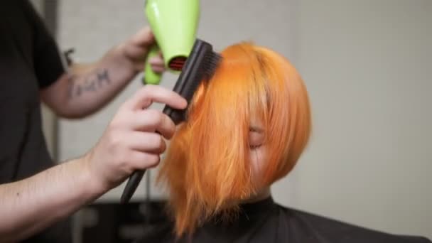 Coiffeur professionnel utilisant un sèche-cheveux après la coupe de cheveux. Jeune rousse dans un salon de beauté. Coup de ralenti — Video