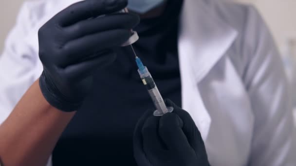 Closeup view of an unrecognizable professional doctor in black gloves and mask with medical syringe in hands, getting ready for injection — Stock Video