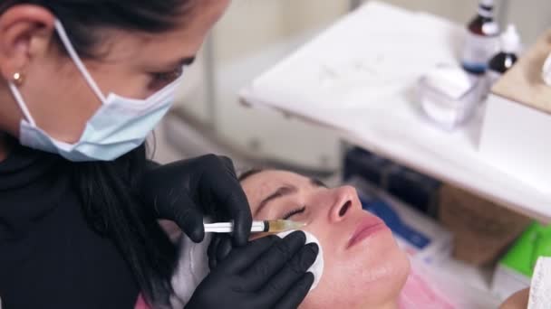 Профессиональный комсетолог в маске делает несколько инъекций женской щеке во время мезотерапии. Биоревитализация и подтяжка лица, нехирургическое лечение — стоковое видео