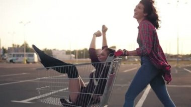 Yan görünüm içinde onu kız arkadaşıyla bir bakkal kart Park alışveriş merkezi tarafından günbatımı sırasında bastırmak mutlu bir genç kadın. Slowmotion atış