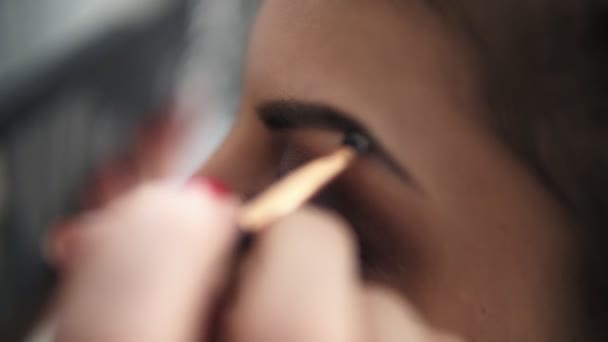 Vista de cerca de las manos de los maquilladores usando pincel para pintar cejas para un modelo con pestañas falsas. Disparo en cámara lenta — Vídeos de Stock