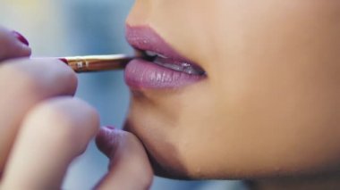 Portre profesyonel makyöz güzellik moda sektöründe çalışan modelleri dudaklarında ruj uygulama görünümünü. Özel fırça kullanarak bir sanatçı el closeup görünümü. Slowmotion