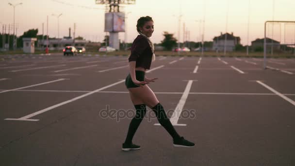 Aantrekkelijke sexy vrouw in de top van het gewas, knie, sokken en shorts dansen op de parking tijdens zonsondergang in de zomer. Sexy beweegt. Tikje schot — Stockvideo