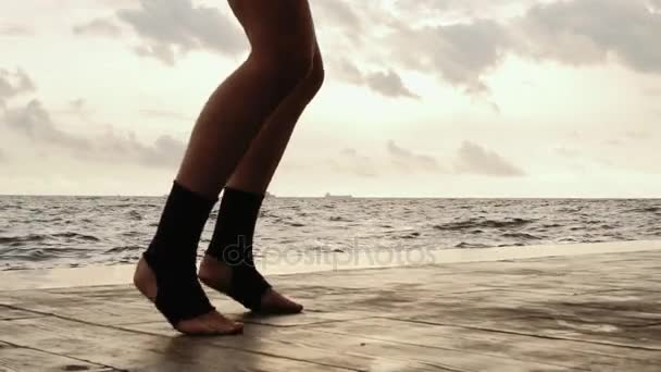 Видео в высоком темпе: Женские ноги боксеров двигаются во время тренировки. Женщина тренируется на пляже. Крупный план на ногах — стоковое видео