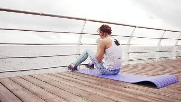 强的年轻女运动员在清晨做仰卧起坐海运垫上。健身女人 abs 仰卧起坐。Abs 的锻炼 — 图库视频影像