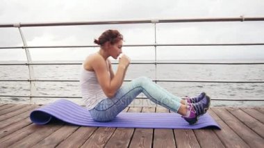 Genç atletik kadının situps okyanus tarafından mindere sabahın erken saatlerinde yapması closeup görünümü. Fitness kadın ABS egzersizi yapıyor. Abs antreman