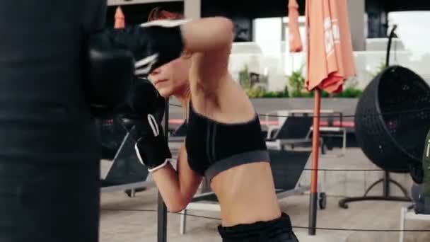 Boxe feminino atlético forte em luvas perfurando um saco. Treino lá fora. Treino de pugilista feminino. Conceito de autodefesa — Vídeo de Stock