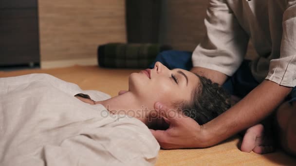 Mujer atractiva joven con los ojos cerrados está recibiendo masaje en el cuello por masajista tailandés masculino. Vista de cerca. Disparo en 4k — Vídeo de stock