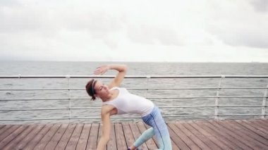 Atletik genç kadın backbending ve okyanus tarafından sahilde germe. Pozisyon yengeç. Slowmotion atış
