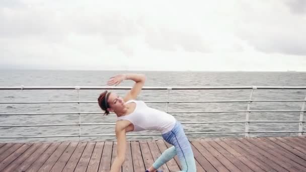 Atletische jonge vrouw backbending en op het strand door de Oceaan te strekken. Krab positie. Tikje schot — Stockvideo