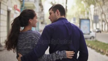 Yakın çekim geri görüntülemek genç güzel çiftin sokak birbirlerine kucaklayan ve konuşmaya yürüyüş. Romantik Tarih