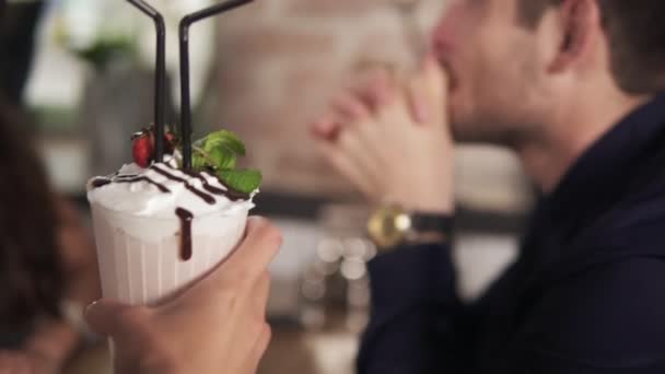 Clseup vista de un cóctel traído por el camarero para la joven pareja sentada en la mesa de madera en la cafetería — Vídeo de stock