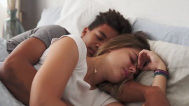 Yatakta yatan ve birbirlerine kucaklayan süre uyku çok ırklı çift portre görünümü. Genç aile kavramı
