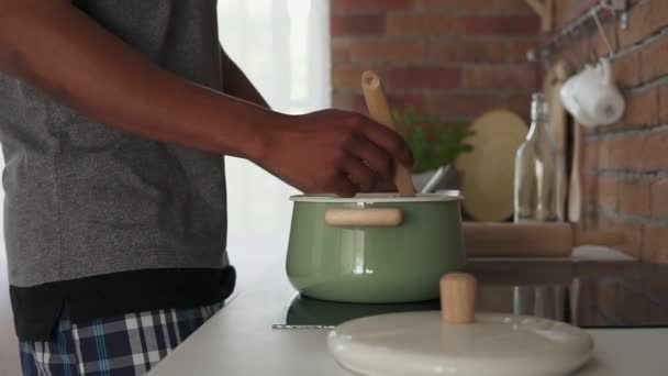 Afrikaanse man kokend water in de pot staan in de keuken, slow-motion shot — Stockvideo