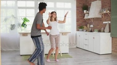 Mutfakta sabahları evde müzik pijama giymiş dans mutlu çok ırklı çift. Slowmotion atış