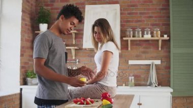 Limon kesme ve beyaz kız mutfakta masada oturan ve gülen komik bir biçimde bu suyu sıkma salata, hazırlama Afrika yakışıklı olan