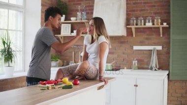 Sabah erkenden mutfakta sohbet çekici çok ırklı çift Slowmotion vurdu. Yakışıklı adam karısını kahvaltı yemek yaparken besleme