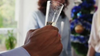 Closeup görünümü el ile köpüklü şarap Noel şapka giymiş ve Noel ve yeni yıl ofiste kutluyor gözlük tungur Ofis çalışanları çok ırklı grup