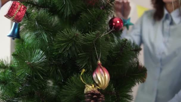 Vista da vicino di un piccolo albero di Natale artificiale decorato da felici impiegati sorridenti. Natale e Capodanno in ufficio. Colpo di rallentamento — Video Stock