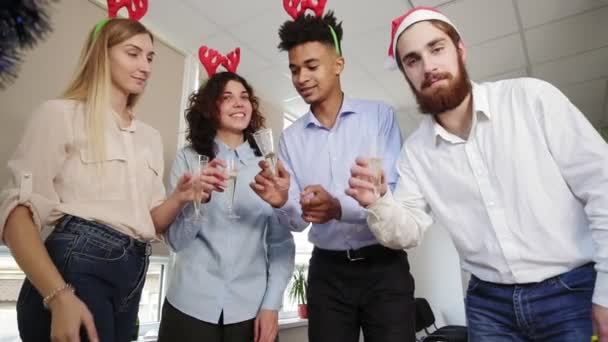 Equipo feliz en los sombreros de santa haciendo llamada de conferencia y tintineo vasos con vino espumoso en la fiesta de la oficina corporativa. Vista desde el ordenador — Vídeo de stock