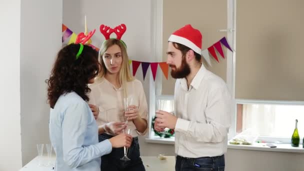 Молодые офисные работники разговаривают и держат бокалы с игристым вином во время рождественской вечеринки в офисе, в то время как их африканский коллега ходит луной, глядя в камеру. Слоумоция — стоковое видео