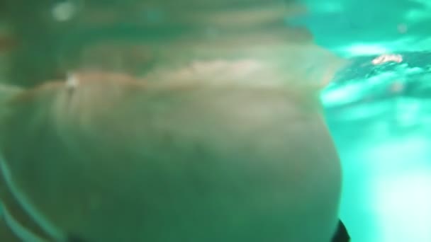 Aranyos szőke kisgyermek védőszemüveg az úszás a medencében a víz alatt, addig, amíg az anyja van felemelve őt a vízből. Egy víz alatti szemcsésedik — Stock videók