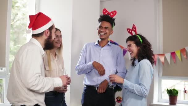 Grupo multiétnico de trabajadores de oficina felices sosteniendo vasos con vino espumoso y hablando durante la fiesta de Navidad en la oficina, sonriendo y riendo. Disparo en cámara lenta — Vídeos de Stock