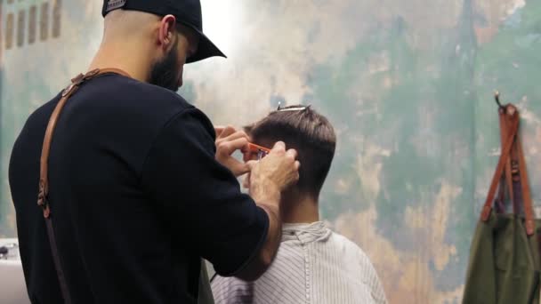 Jonge knappe Kaukasische man krijgt een kapsel in een moderne kapper. Styling met elektrische trimmer van een bebaarde barber. Tikje schot — Stockvideo