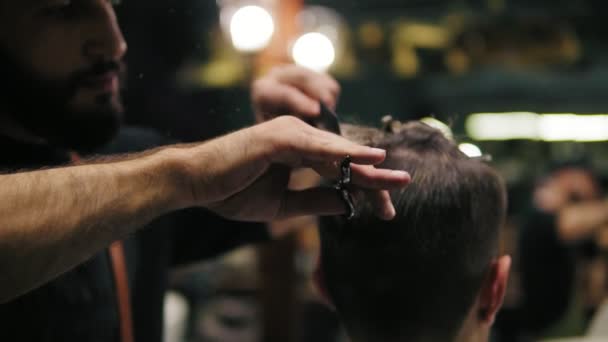 Vista da vicino delle mani dei barbieri che eseguono un taglio di capelli con le forbici e pettinano il cliente. Colpo di rallentamento — Video Stock