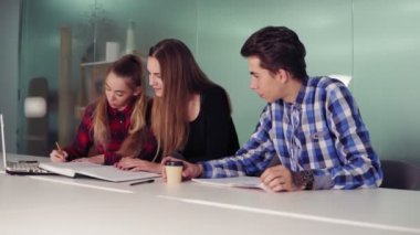 Modern daire toplantıda gençlerin grup. Üç öğrenci ödevlerini birlikte masada oturan ve kahve içme üzerinde çalışıyor. Slowmotion atış