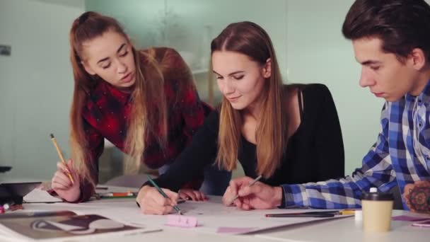 Gruppe junger Kreativer, die in modernen Büros zusammenarbeiten. junge Profis, die am Tisch Skizzen machen, ihr neues Projekt vorbereiten und in Zeitlupe Kaffee trinken — Stockvideo