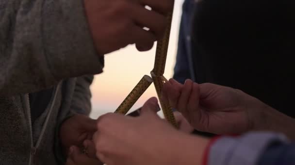 Grupo de amigos sosteniendo velas brillantes y aligerándolas en la playa durante el atardecer — Vídeo de stock