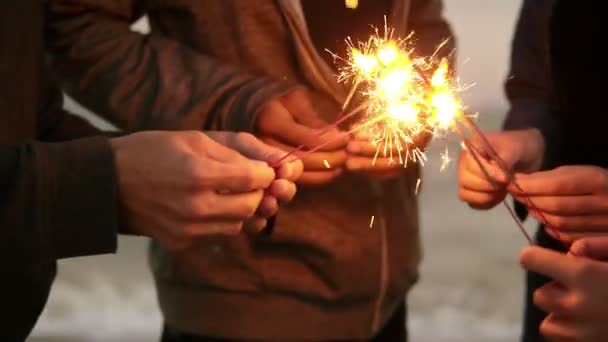 Προβολή closeup των χεριών της ομάδας των ανθρώπων που κατέχουν Βεγγάλη φώτα και τους lightening επάνω στην παραλία κατά τη διάρκεια του ηλιοβασιλέματος — Αρχείο Βίντεο