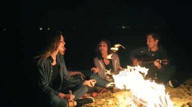 Gençler neşeli şarkılar tarafından bira içme gitar çalmak şenlik gece, geç saatte. Neşeli arkadaşları konuşuyor ve having fun