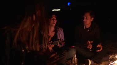 Şenlik ateşi tarafından geç gece ve şarkıları söyleyerek oturma ve gitar çalmak gençlerin çok ırklı grup. Neşeli Afrika kökenli Amerikalı arkadaşları için gitar çalmak