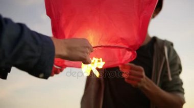 Kırmızı kağıt fener başlatmadan önce tutan genç çok ırklı çift portre görünümü. Gün batımı sırasında sahilde romantik Tarih boyunca Afrika sevgilisi ile çekici kadın