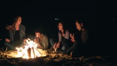 Genç erkek ve kızlar tarafından şenlik geç gece ve şarkıları söyleyerek oturma ve gitar çalmak çok ırklı grup