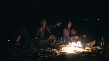 İki sevimli birbirlerine kucaklayan ve şenlik ateşi tarafından geç gece yıldızlara bakarak otururken çiftler