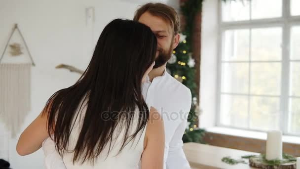 Gelukkige aantrekkelijke jonge paar in liefde dans samen in hun stijlvolle appartement door de kerstboom — Stockvideo