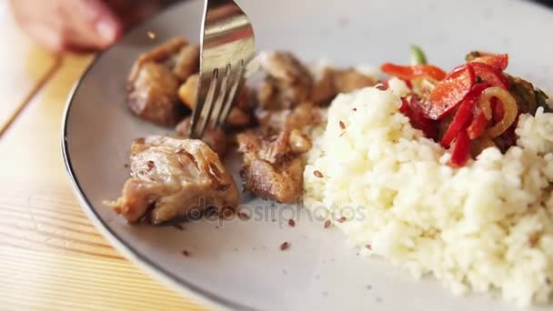 Mouvement de la caméra de la plaque avec du riz et de la viande aux femmes visage. Gros plan d'une jeune femme utilisant une fourchette pour prendre de la viande frite avec du riz dans son assiette. Déjeuner au café — Video