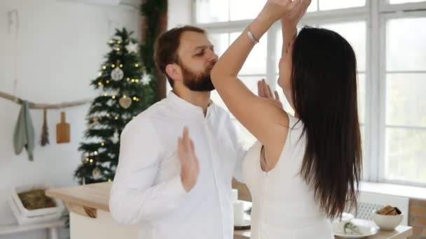 Feliz casal jovem e atraente no amor dançam juntos em seu elegante apartamento junto à árvore de Natal. Adorável jovem família em casa — Vídeo de Stock