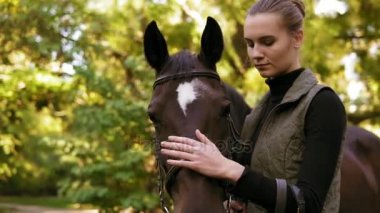 Genç güzel kadın sevişme kahverengi atı duran yeşil alanda closeup görebilmek