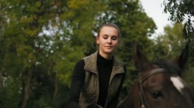 Genç güzel kadın kahverengi at eyer oturan ve kafasını atları kafasına koyarak süre okşayarak closeup görünümü