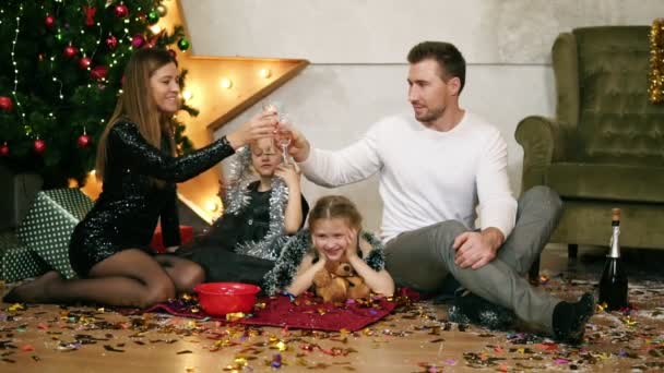 El marido sonriente y su esposa están tintineando copas con champán. Linda madre, padre y dos hijas celebrando la Navidad juntos — Vídeo de stock